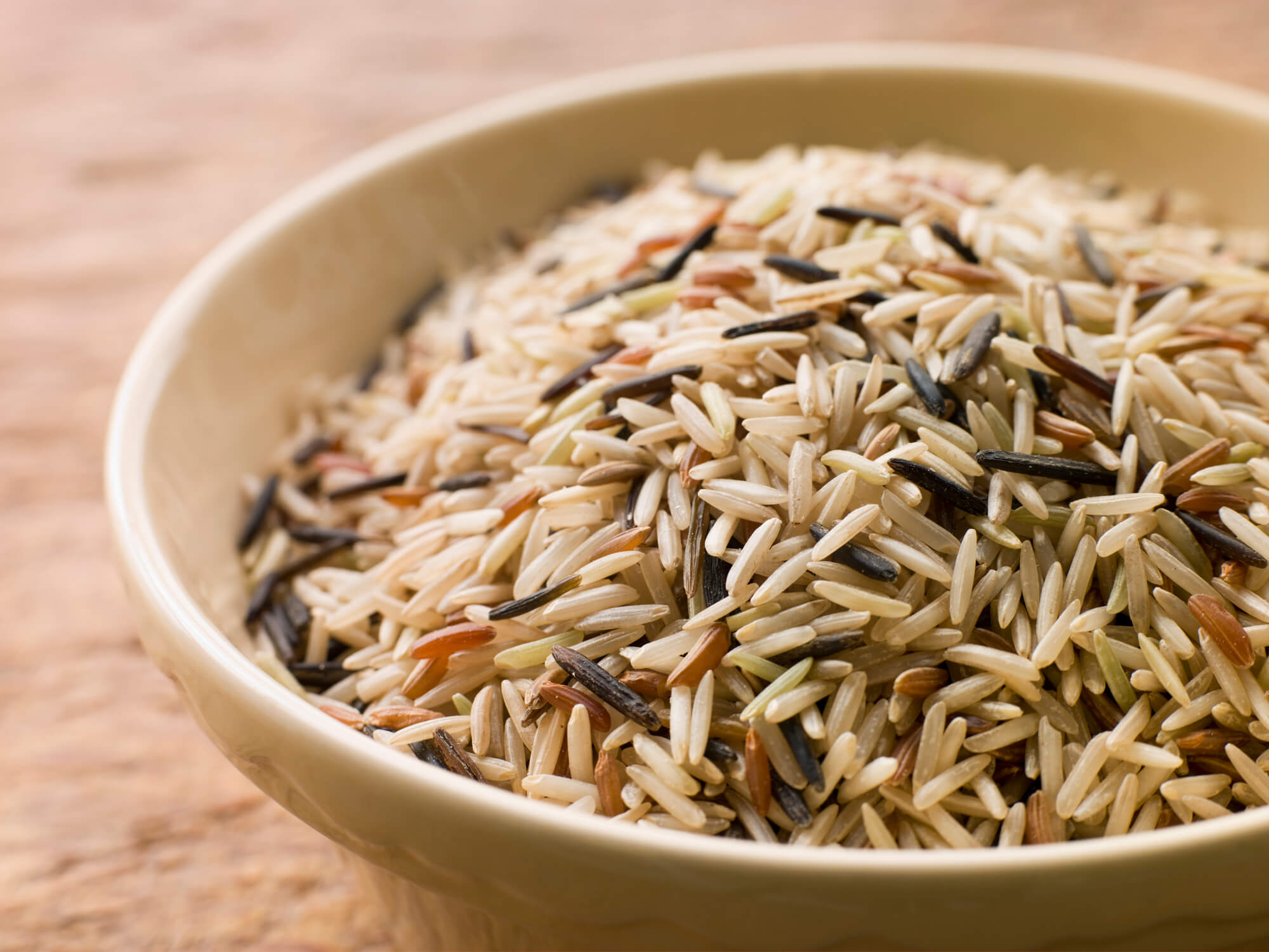 Learn how to cook wild rice in a rice cooker by Rice Cooker Guy. Image of a bowl of uncooked wild rice.