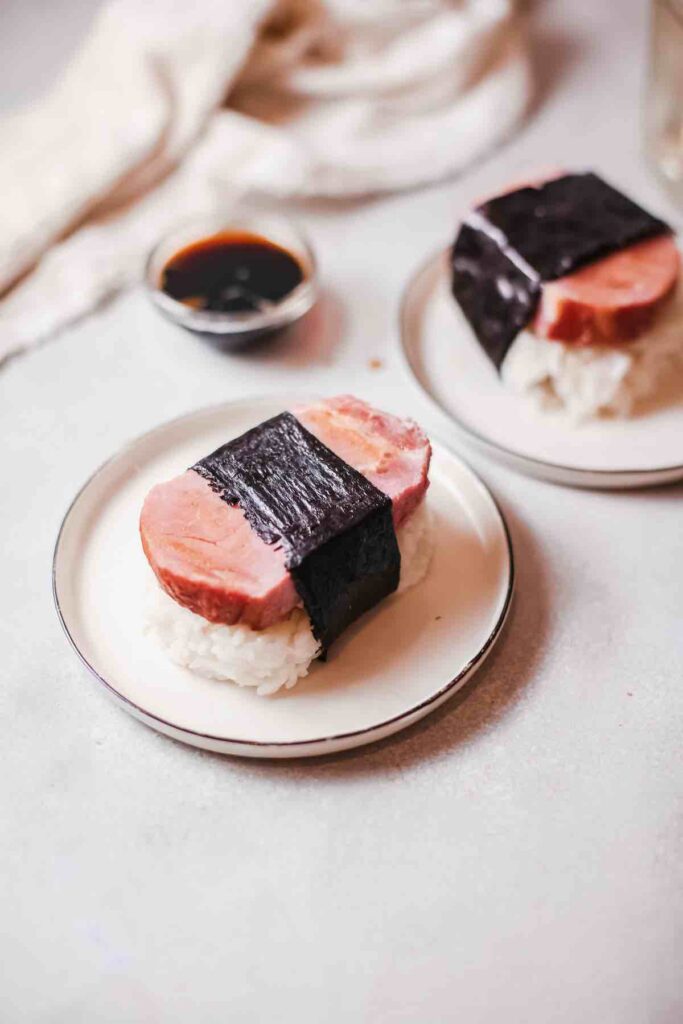 Image of Spam on rice wrapped with seaweed on a plate.