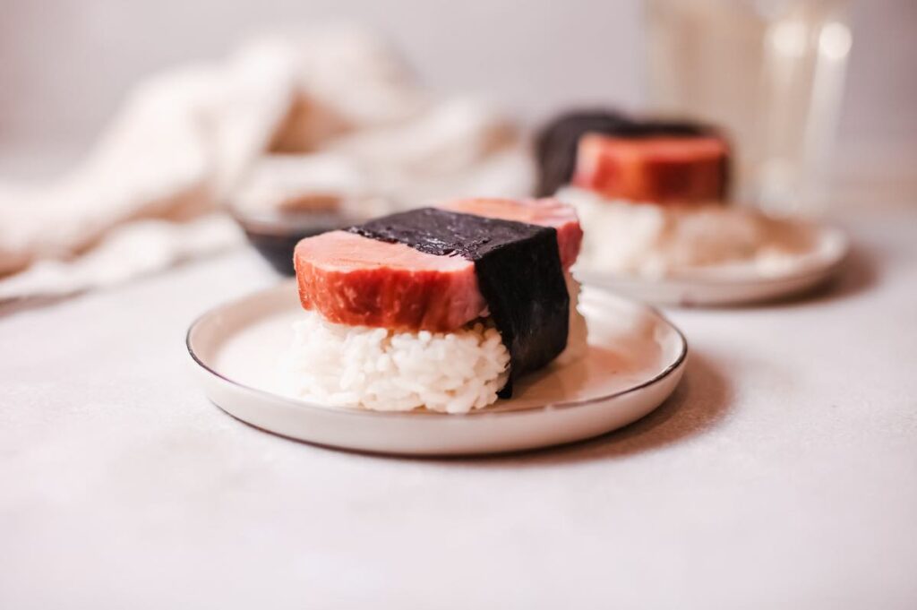 Image of a slice of Spam on a bed of rice that's wrapped with a strip of seaweed.